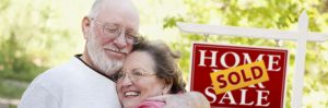 Elderly couple embracing as house sold